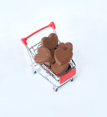 chocolate hearts in shopping trolley on white background. sweets Valentine's Gift. creative minimal concept. copy space