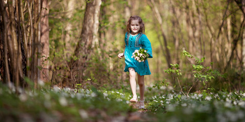 Little girl  taking a walk all alone in a park or forest.  Cute girl running on the road in the park on a sunny day. Spring or summer time. Copy space for text. Banner