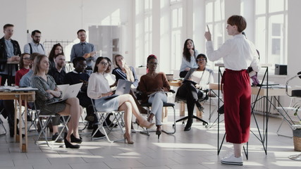 RED EPIC Young short haired business woman giving seminar talk at modern office, multiethnic team clapping slow motion.