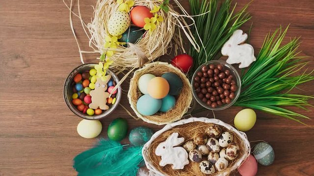 Hands holding basket full of colorful Easter eggs in front of decoration on wooden table. Easter holiday decorations, Easter concept background.