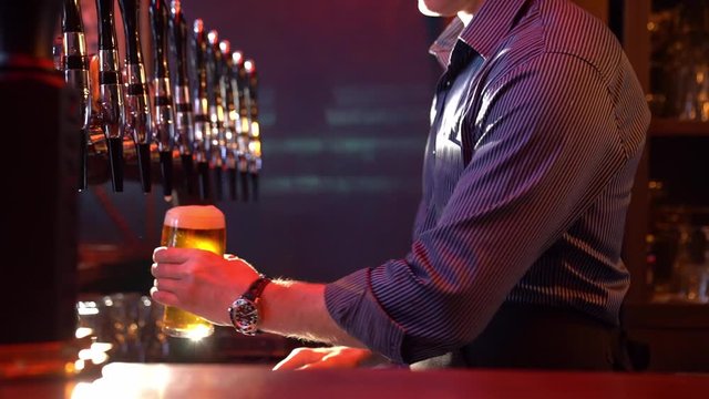 A bartender pours beer from keg and puts on table 