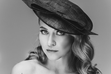 Studio portrait of an immaculate lady with natural makeup, blonde wavy hair and blue eyes wearing stylish black hat. Topless woman with nude makeup in fashionable black hat looking at camera. Cutout