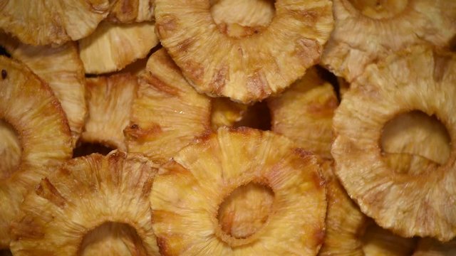 Slices of dried pineapple on rotating background. Top view. Vegan, vegetarian diet. Healthy lifestyle. Dried fruits background. Sweet pineapples, organic food.