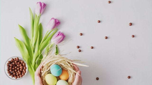 Hands picking up nest with Colorful Easter eggs on bright background. Easter holiday decorations , Easter concept background.