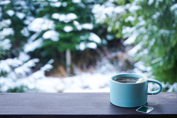 Menthol tea cup on wooden railing and forest background, space for text.