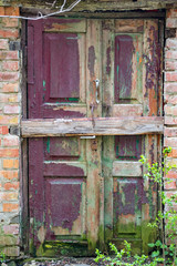 Vintage wood door in legacy building with peeling red paint.
