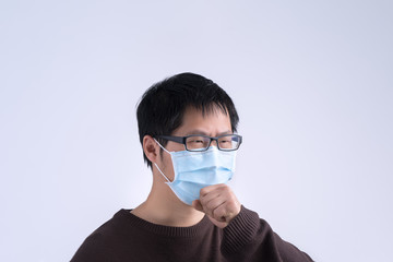 Young Asian man is coughing, feeling unwell, vomit sick with wearing a medical blue face mask isolated on white background, close up, copy space.