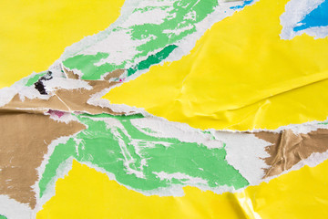Yellow and green torn paper placards on billboard with old ripped and peeling posters texture...
