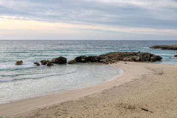 Beach in the middle of winter with cloudy sky on the coast of Taranto, Puglia, Italy