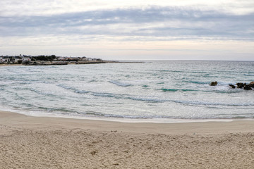Beach in the middle of winter with cloudy sky on the coast of Taranto, Puglia, Italy