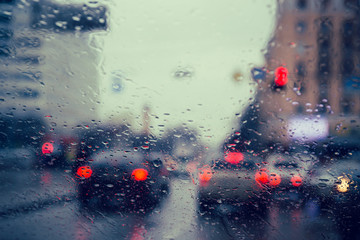 City road seen through rain drops on the car windshield.