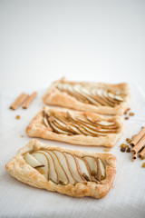 Crunchy puff pastry pie. Homemade baked pie with pears. Top view. Delicious dessert with sliced pear and chocolate powder.
