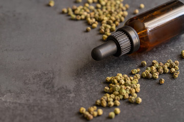 Grenn pepper essential oil and green peppercorns on black background for beauty and natural...