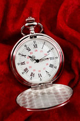 Countdown deadline, precision instrument and nostalgic jewelry open lid retro silver pocket watch with minutes, hours and seconds hands isolated on red velvet