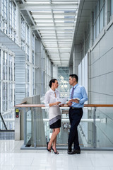 Business woman talking with business partner while standing in modern corridor stock photo