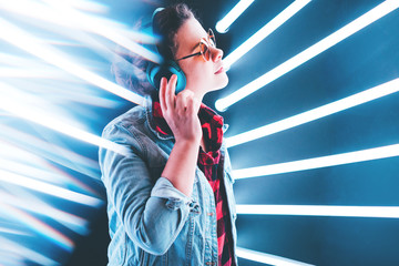 Fototapeta premium Woman in headphones listening music in blue neon light.