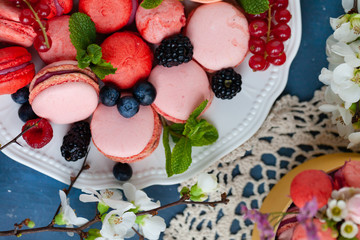 Colorful and bright delicious homemade traditional french dessert - elegant macarons. Natural fruit and berry flavors, sweet creamy stuffing. Top view, flat lay, close up, macro. Dark blue background