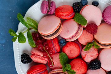 Colorful and bright delicious homemade traditional french dessert - elegant macarons. Natural fruit and berry flavors, sweet creamy stuffing. Top view, close up, macro, flat lay. Dark background