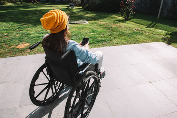 Disabled girl in a wheelchair using her mobile phone.Disable and technology concept