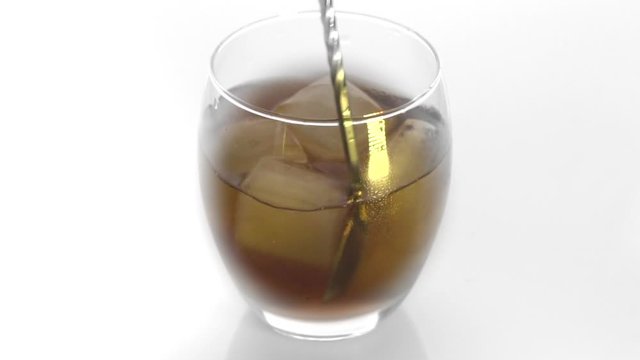 Close-up. Ice cubes rotating and melts in a glass of whiskey. Isolated on white background. Rotating ice bubes in  whiskey on a white background 