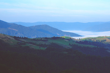 Fototapeta na wymiar Mountain ranges covered with fog against the dawn sky