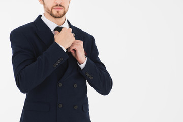 Hands are tightening a tie of the suit of the smart businessman with isolated white background and copy space.  Image white isolated background for the banner.