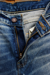 Close up of denim jeans front button. Texture and textile of opened pair of trousers
