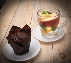 Cupcake, muffin on a white saucer, Cup of fruit tea on a wooden table, close-up, space for text
