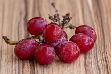 cacho de uvas vermelhas sobre mesa de madeira