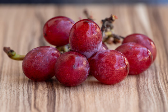 cacho de uvas vermelhas sobre mesa de madeira