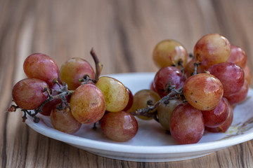 cacho de uvas vermelhas sobre mesa de madeira