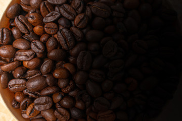 coffee beans in a round bowl close-up. one side in the shadow and not readable