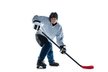 Scoring. Young male hockey player with the stick on ice court and white background. Sportsman wearing equipment and helmet practicing. Concept of sport, healthy lifestyle, motion, movement, action.