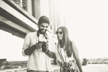 The handsome bearded man just took a very nice photo and shows it to his girlfriend. They are on a journey, they are happy and laughing. Black and white photo.