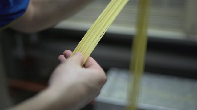 Quality control manager worker checking examining the quality of the raw pasta spaghetti macaroni in an Italian pasta factory, Quality of food production. Automated continuous line.