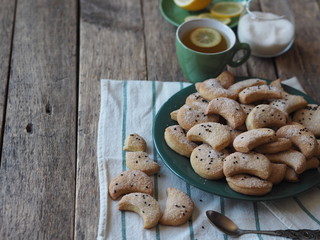 Homemade shortbread cookies sprinkled with sugar with black sesame seeds on a wooden rustic table. Tea party with cookies and lemon. Place for text. Photo for the holiday.