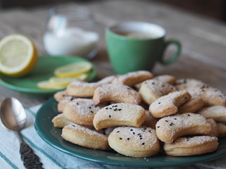 Homemade shortbread cookies sprinkled with sugar with black sesame seeds on a wooden rustic table. Tea party with cookies and lemon. Place for text. Photo for the holiday.