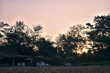 a beautiful sunset behind the trees in a beach in goa