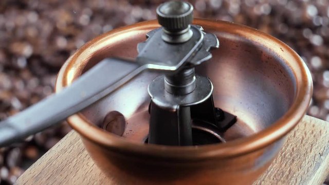 Black coffee beans slowly fall into the grinder 