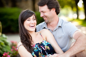 Obraz premium Happy Young Man and Woman Laughing While Sitting on Sidewalk