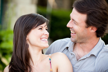 Happy Young Man and Woman Laughing While Sitting on Sidewalk