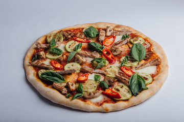 Pizza with slices of meat with basil and pepper. Italian pizza on a white background