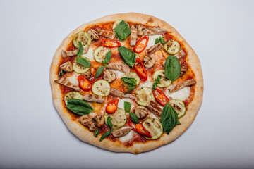 Pizza with slices of meat with basil and pepper. Italian pizza on a white background