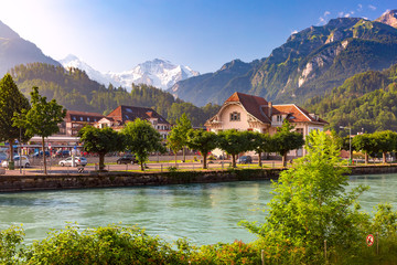 Fototapeta na wymiar Train station and Aare river in Interlaken, important tourist center in Bernese Highlands, Switzerland. The Jungfrau is visible in background