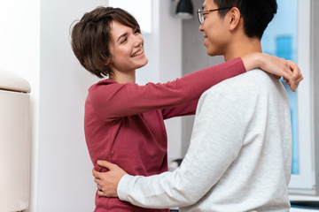 Photo of multinational couple laughing and hugging while dancing