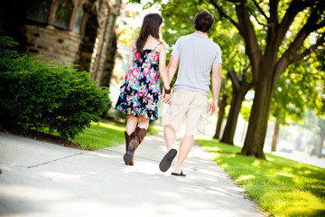Fototapeta na wymiar Young Couple Walking on Sidewalk in Neighborhood