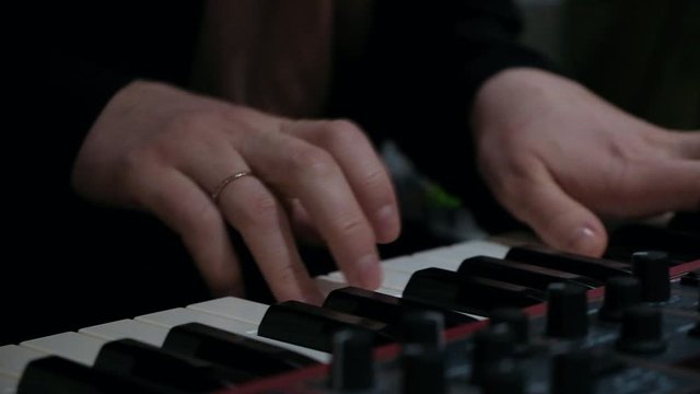 Close up shot of pianist playing on synth live music on cajon with drum brushes