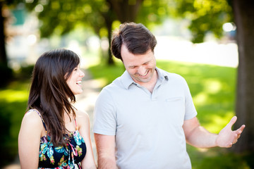 Young Couple Laughing and Walking on Sidewalk in Neighborhood