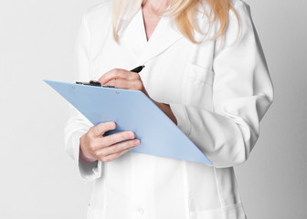 Middle-aged woman holding folder over grey background