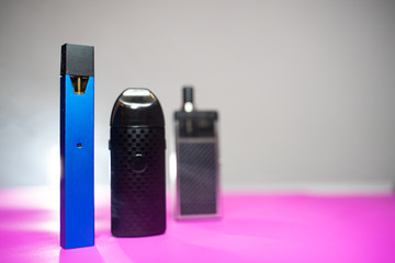 many Electric cigarette pod at the left side on pink ground .
